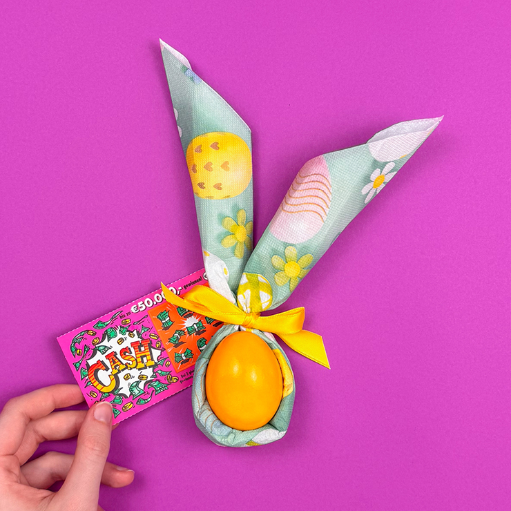 Ein Bild das zeigt, wie ein Rubbellos zum Servietten-Ei dazugelegt wird.