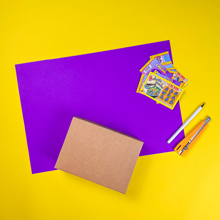 Ein Bild das Geschenkpapier, Cutter, Lose und Stift zeigt. 