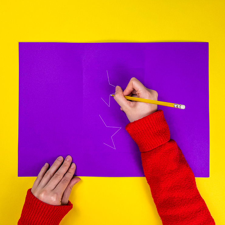 Ein Bild das zeigt, wie die Sterne am Geschenkpapier aufgemalt werden.