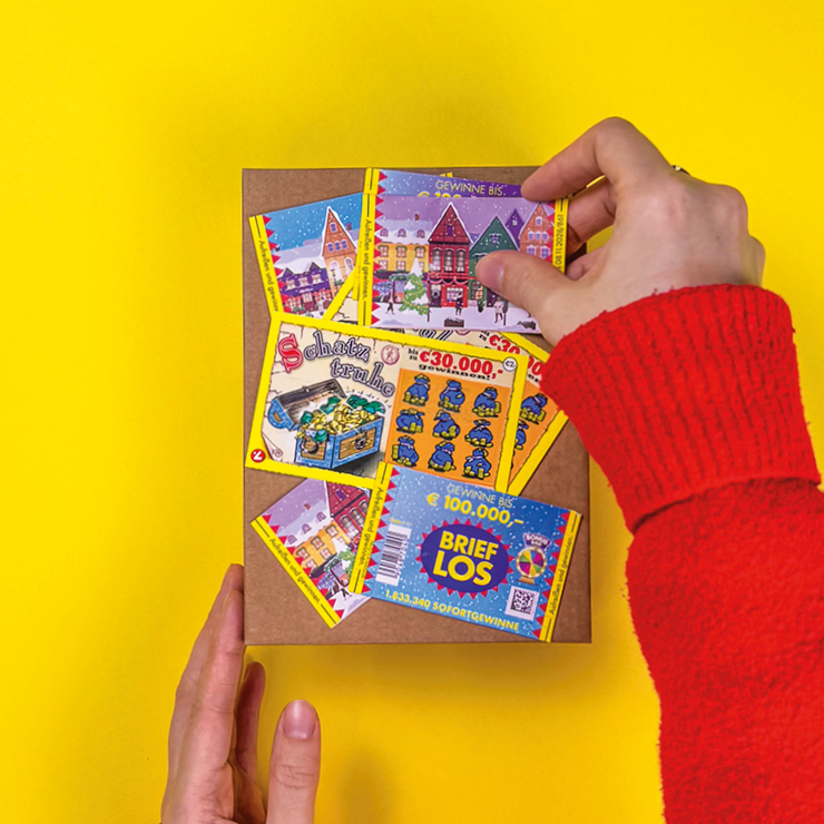 Ein Bild das zeigt, wie Rubbellose und Brieflose auf das Geschenk geklebt werden