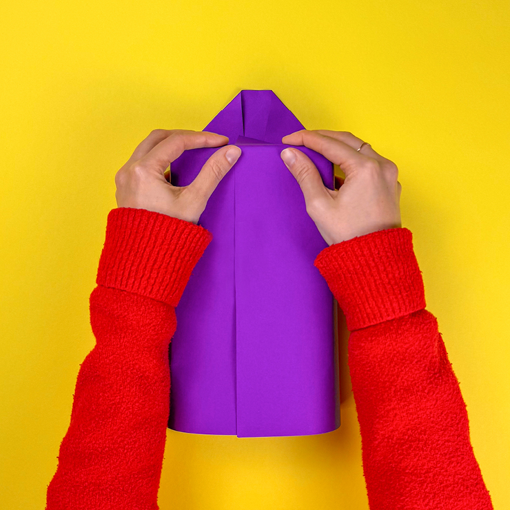 Ein Bild das zeigt, wie das Geschenk mit Geschenkpapier eingepackt wird.