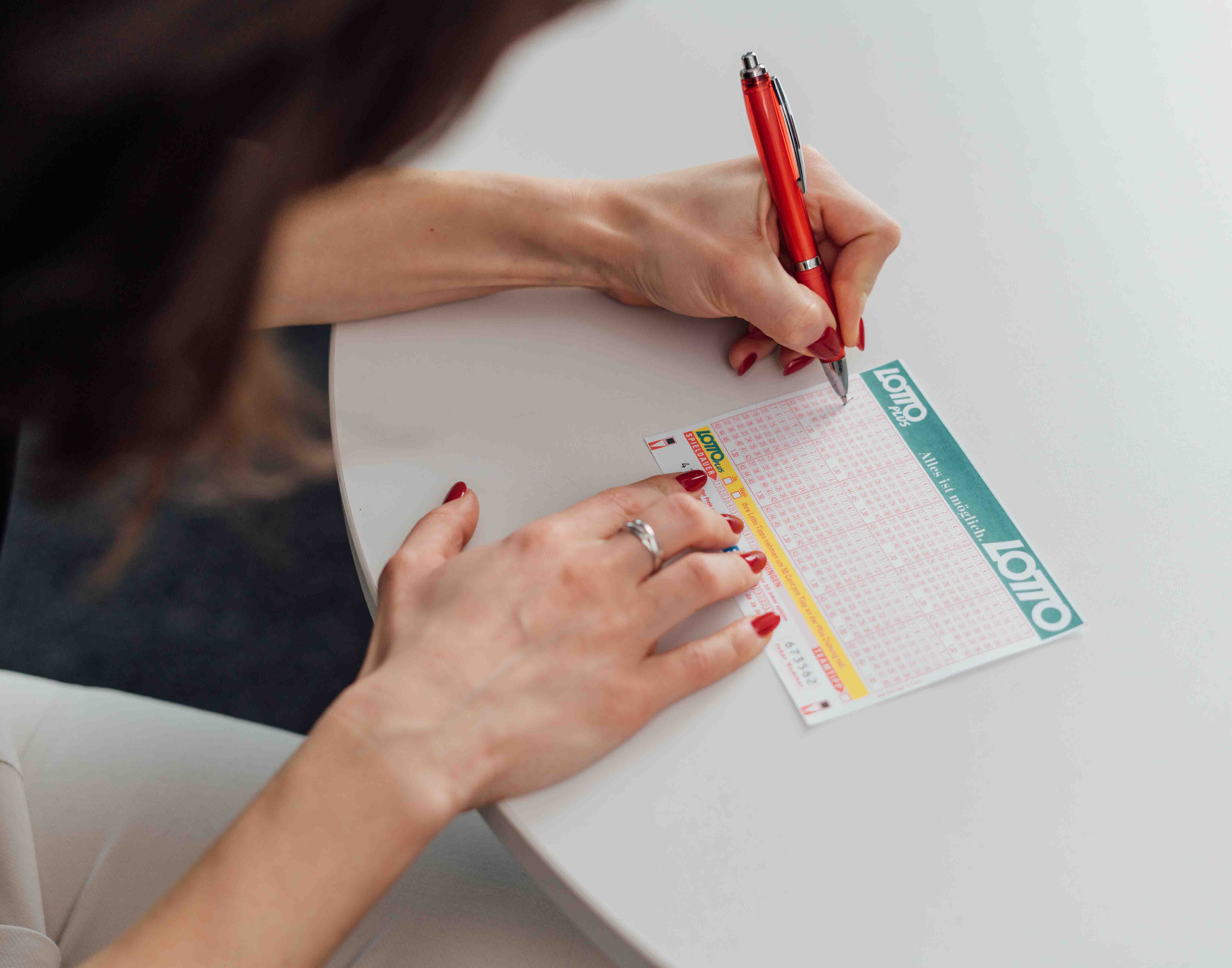 Person füllt einen Lotto und LottoPlus Wettschein aus.