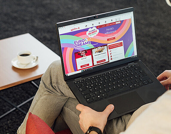EuroDreams online spielen. Person sitzend mit Laptop am Schoß. 
