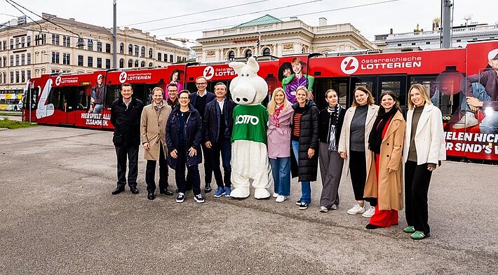 Branding eine Straßenbahn-Garnitur mit der Imagekampagne der Österreichische Lotterien: "Hier spielt alles zusammen. Glücksspiel mit Verantwortung." Foto mit allen am Projekt beteiligten Personen