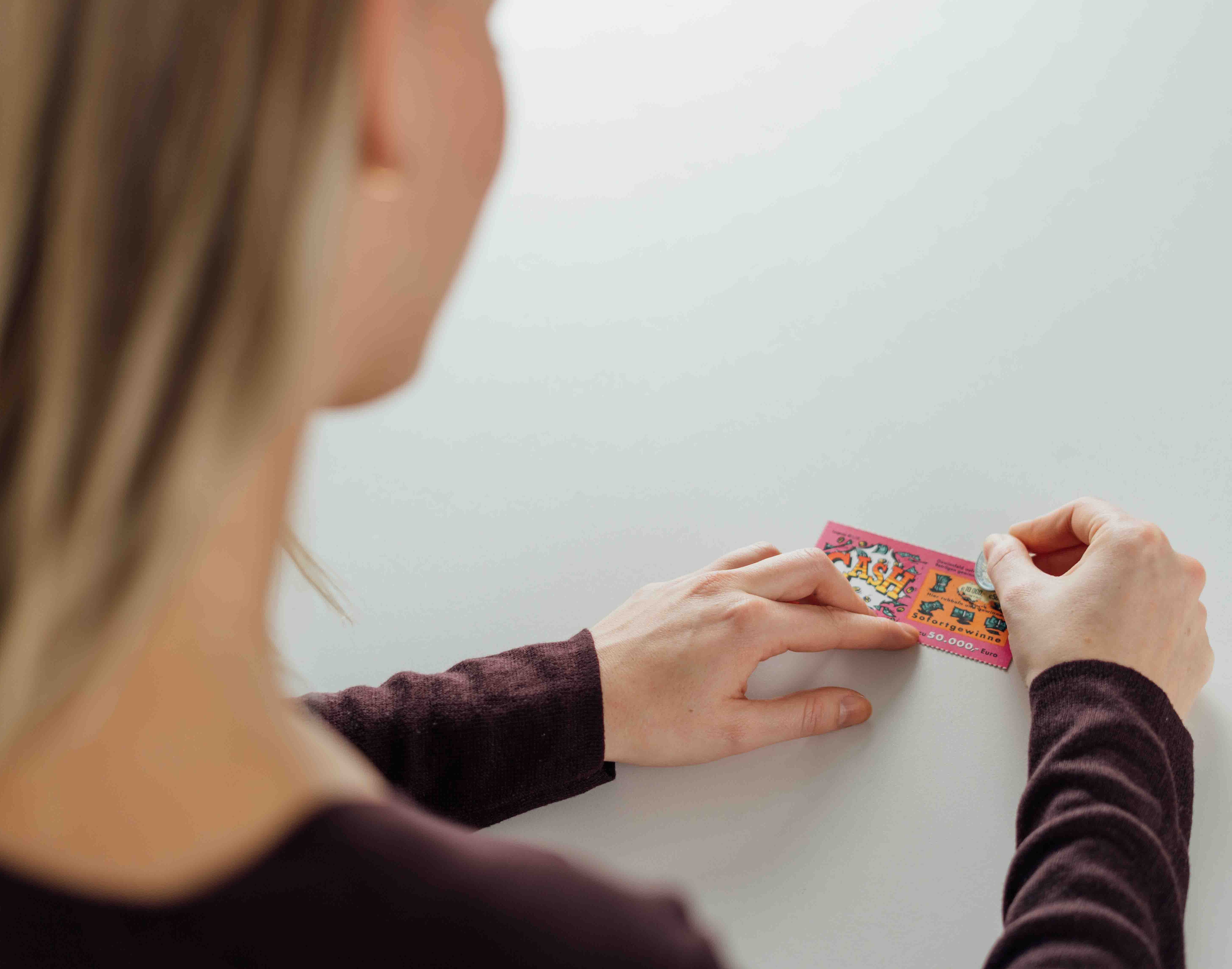 junge Frau rubbelt das Rubbellos Cash auf