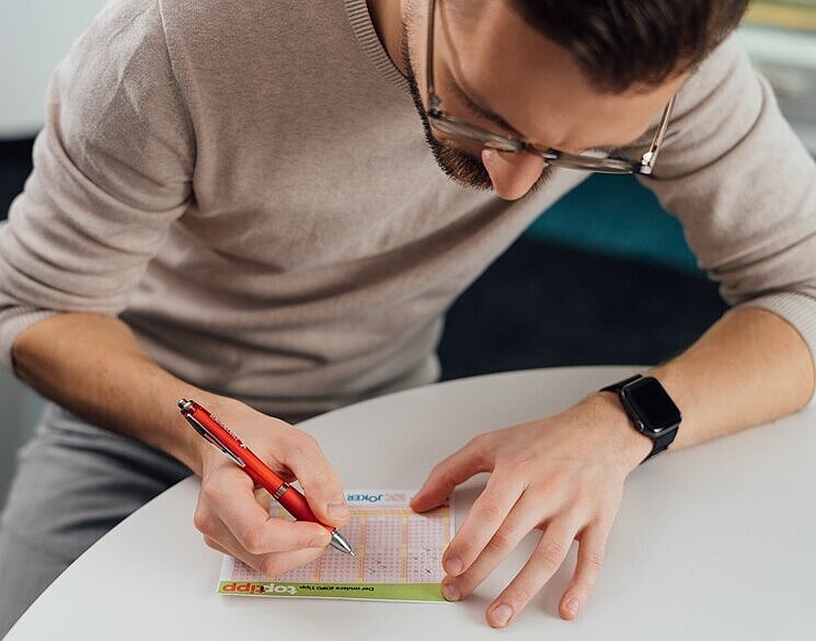 Ein Lotto-Spieler füllt einen Spielschein aus und spielt den Top-Tipp