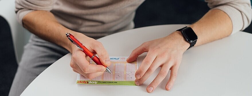 Ein Lotto-Spieler füllt einen Spielschein aus und spielt den Top-Tipp