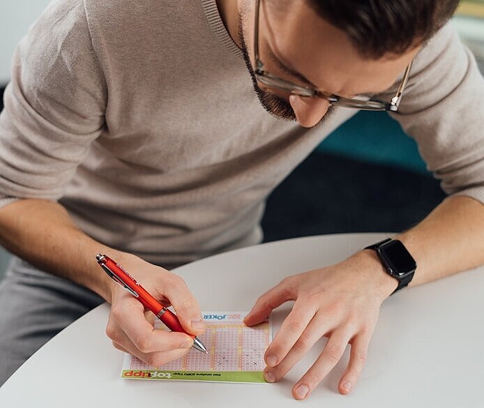 Ein Lotto-Spieler füllt einen Spielschein aus und spielt den Top-Tipp
