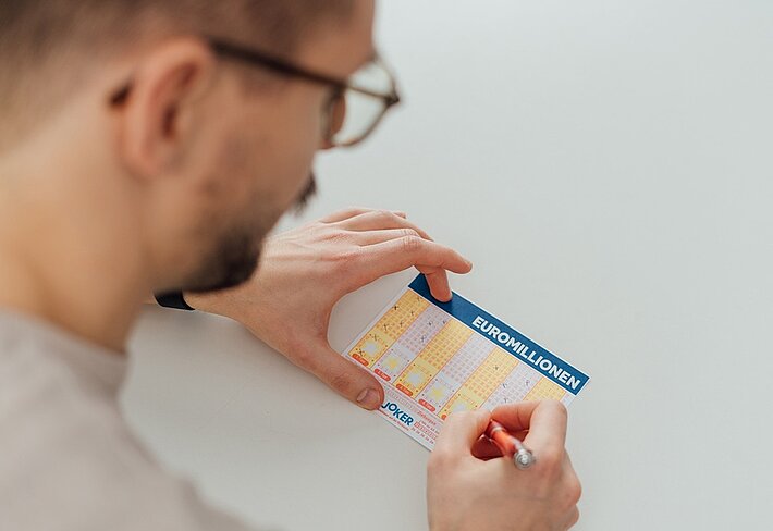 Person füllt EuroMillionen Wettschein aus