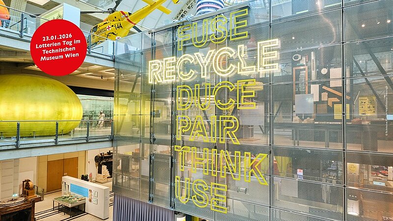 Einblick in das Technische Museum Wien, Gelbe Aufschrift auf einer großen Glaswand: RECYCLE und weitere Begriffe zu dem Thema