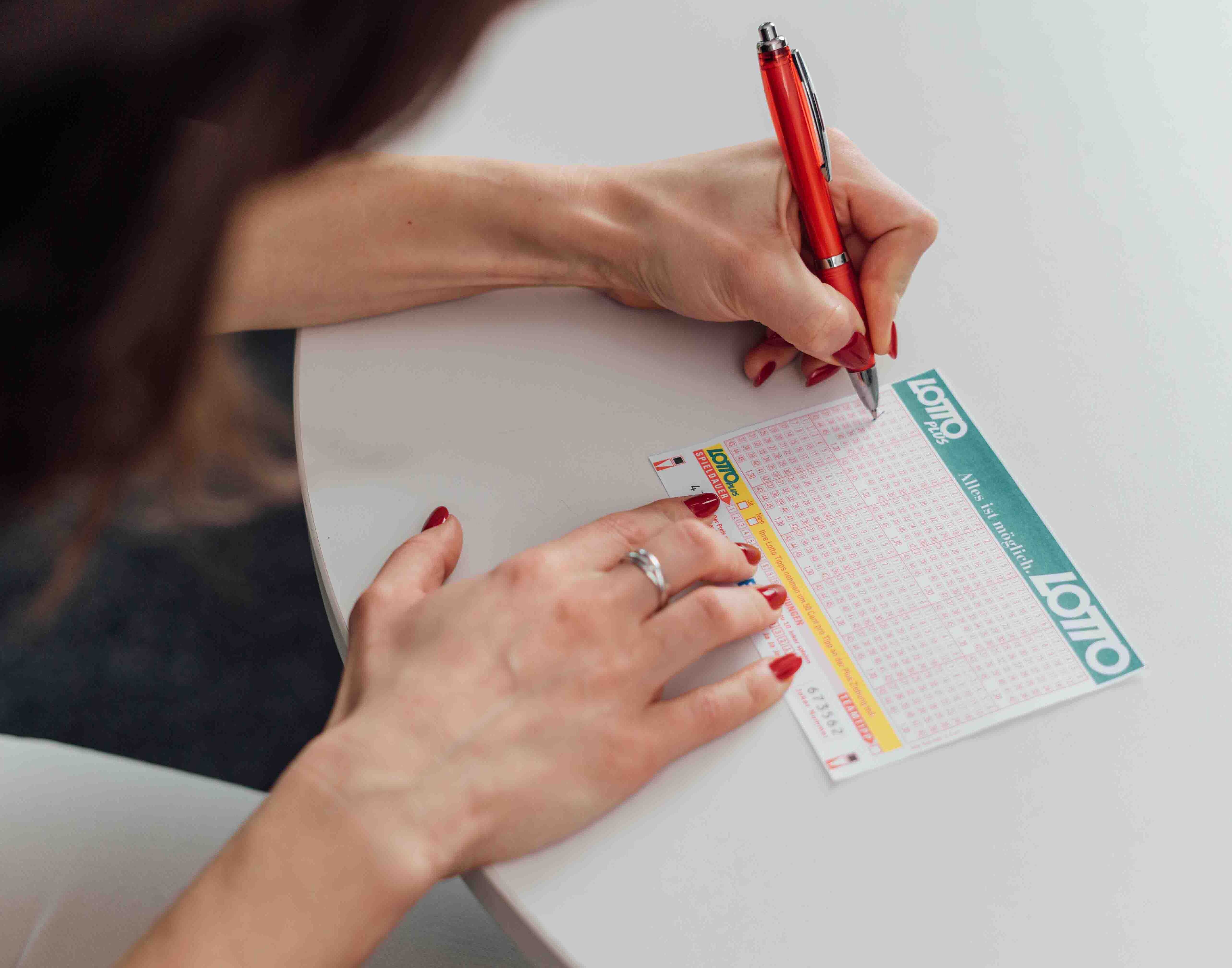 Person füllt einen Lotto und LottoPlus Wettschein aus. 